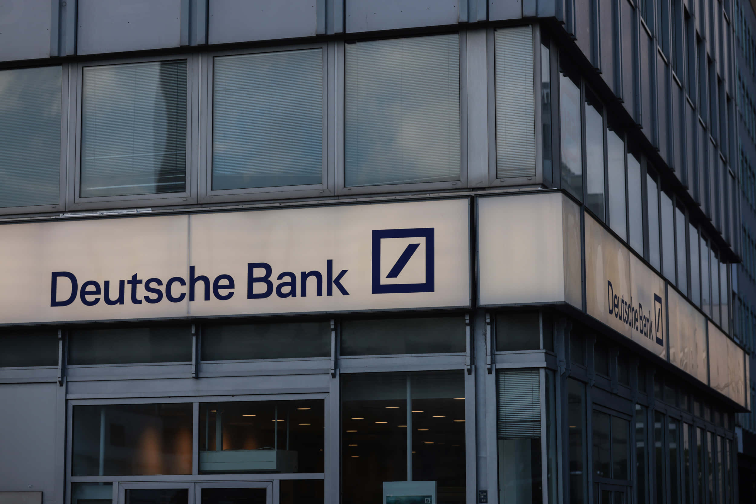 Bank 桌布 壁紙 — 德意志銀行大樓的現代玻璃外牆，在黃昏時分帶有發光標誌。