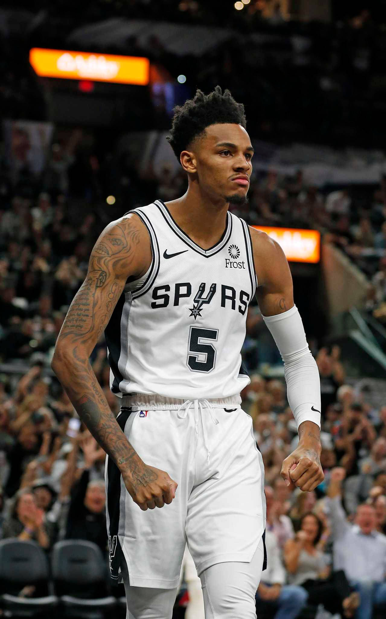 德約恩特·默里NBA球員 壁紙 — 一名專注的籃球運動員身穿白色馬刺隊5號球衣，在燈光明亮的球場上行走，周圍是歡呼的球迷。