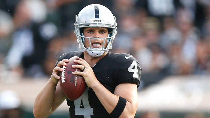 穿著Raiders隊服的NFL四分衛在比賽中準備投擲橄欖球。