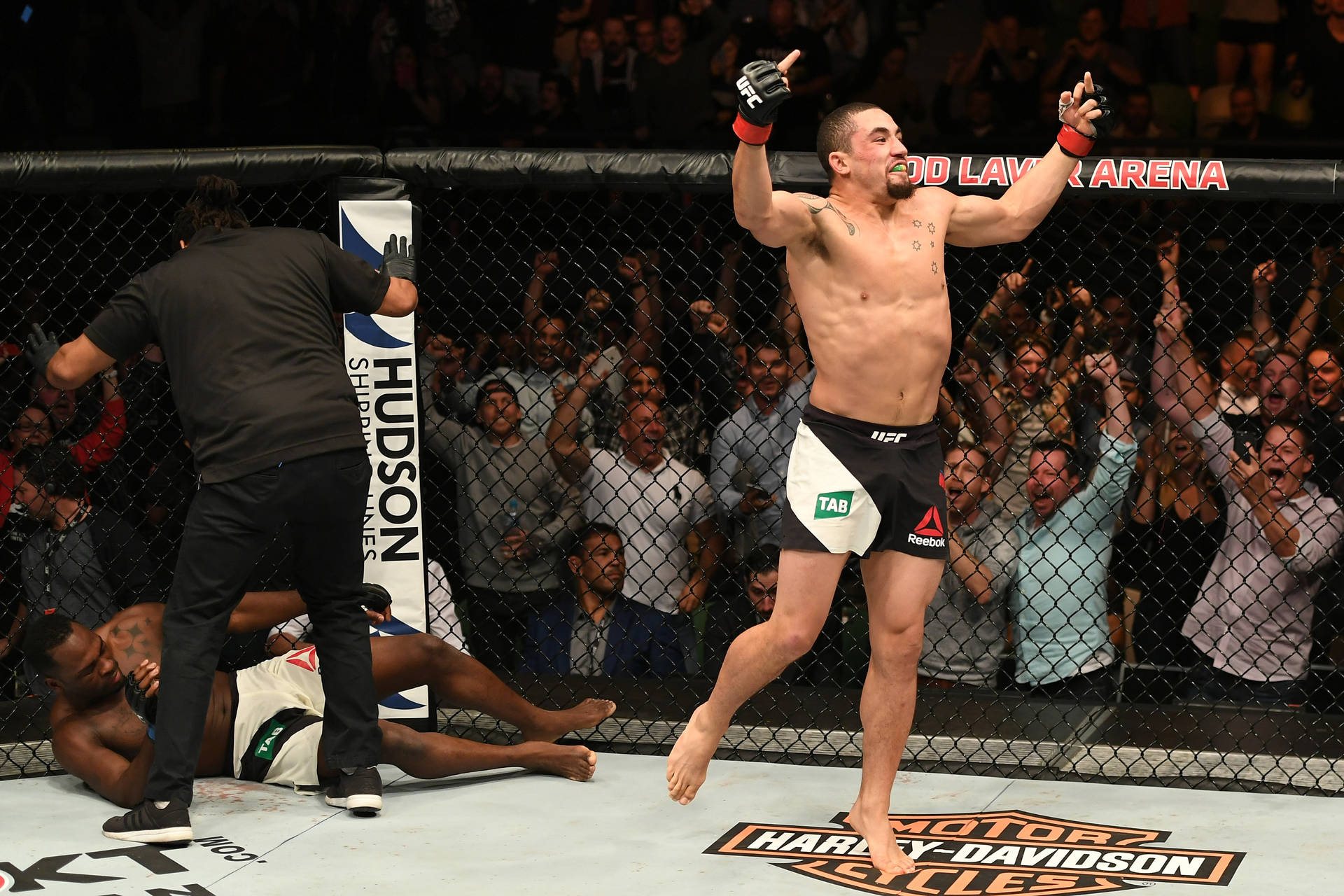 MMA拳手在八角籠中擊敗對手後高舉雙臂慶祝勝利。