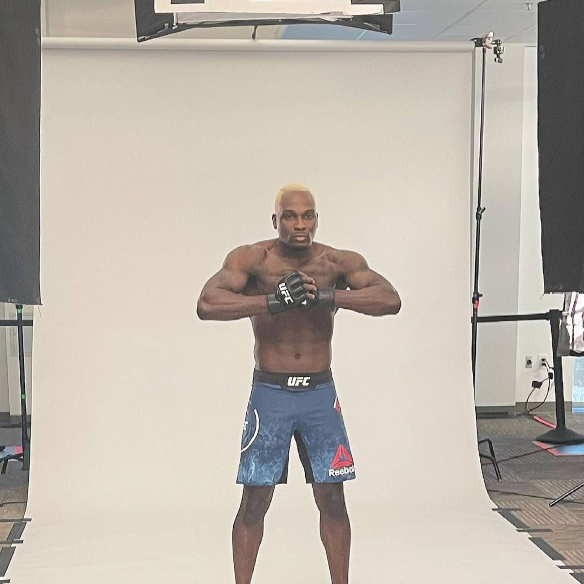 一位穿著藍色UFC短褲和手套的肌肉發達MMA戰士在工作室中擺姿勢。