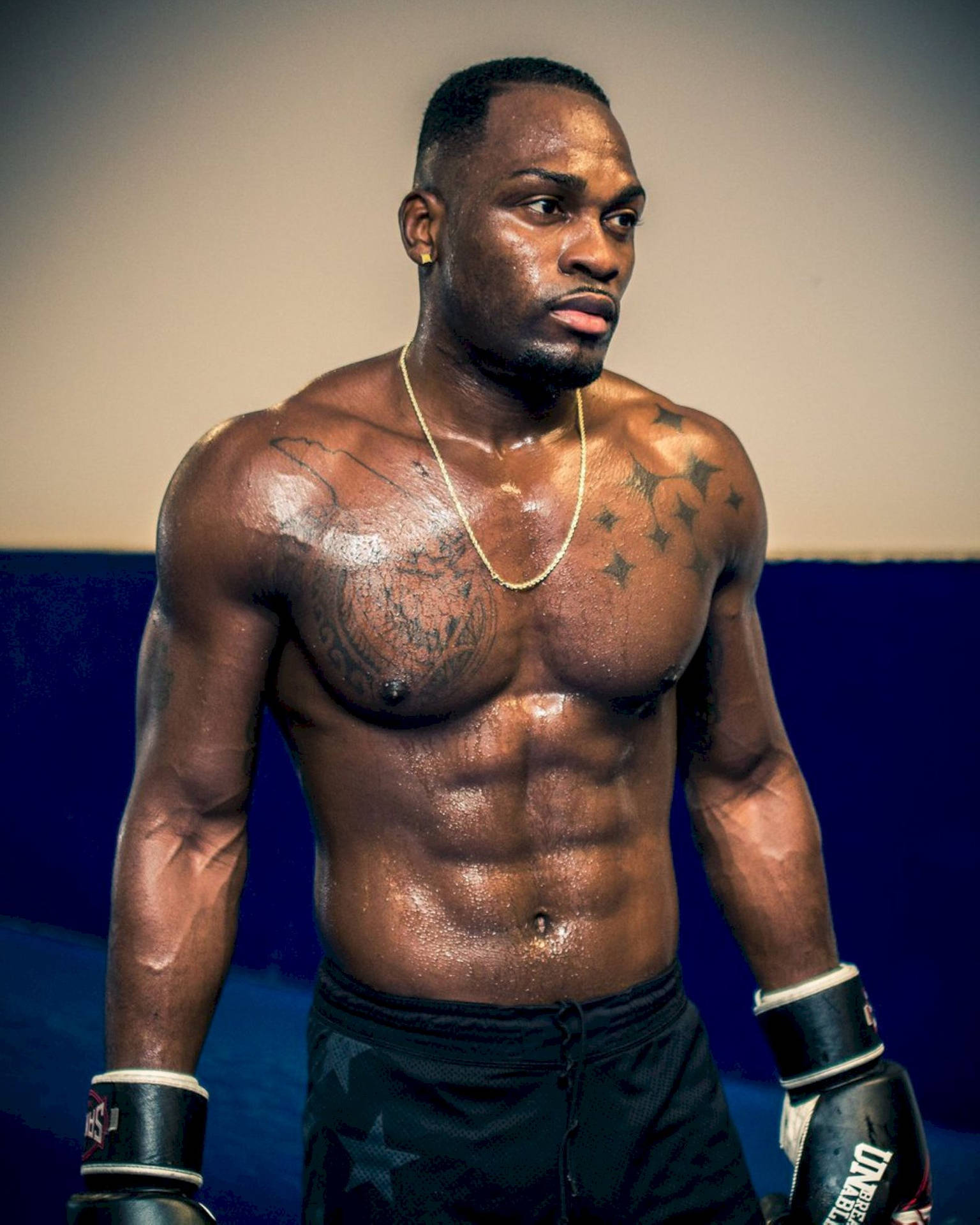 一個汗流浹背、肌肉發達的拳擊手戴著手套在訓練中專注地凝視。