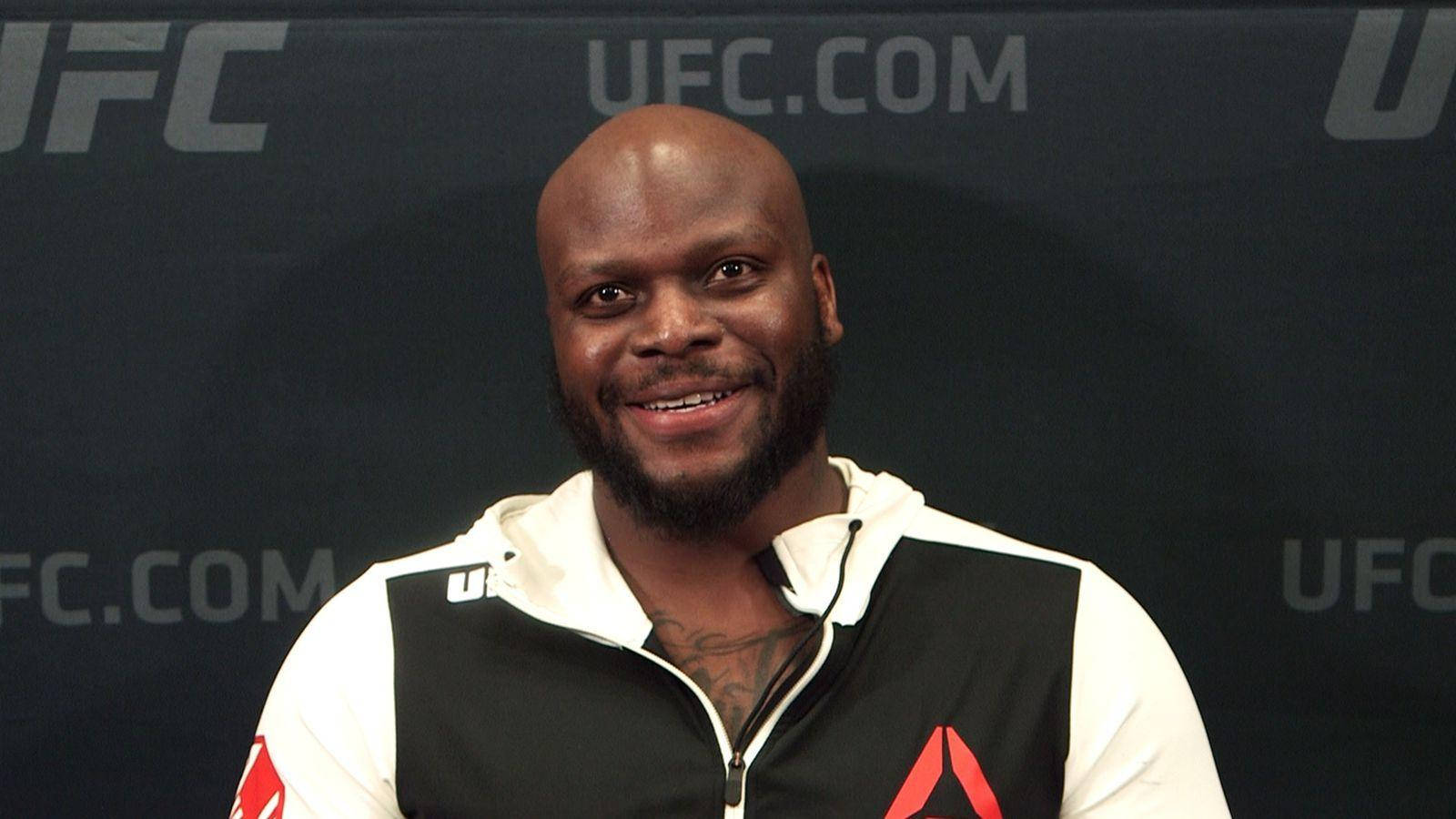 留鬍鬚的黑人男性在記者會上穿著UFC連帽衫微笑。