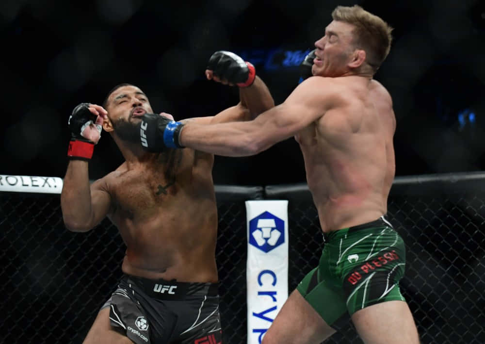 德里庫斯·杜普雷西斯比賽中揮拳 壁紙 — 兩名MMA拳手在激烈的鐵籠賽中交鋒，其中一人向對手面部打出強力一拳。