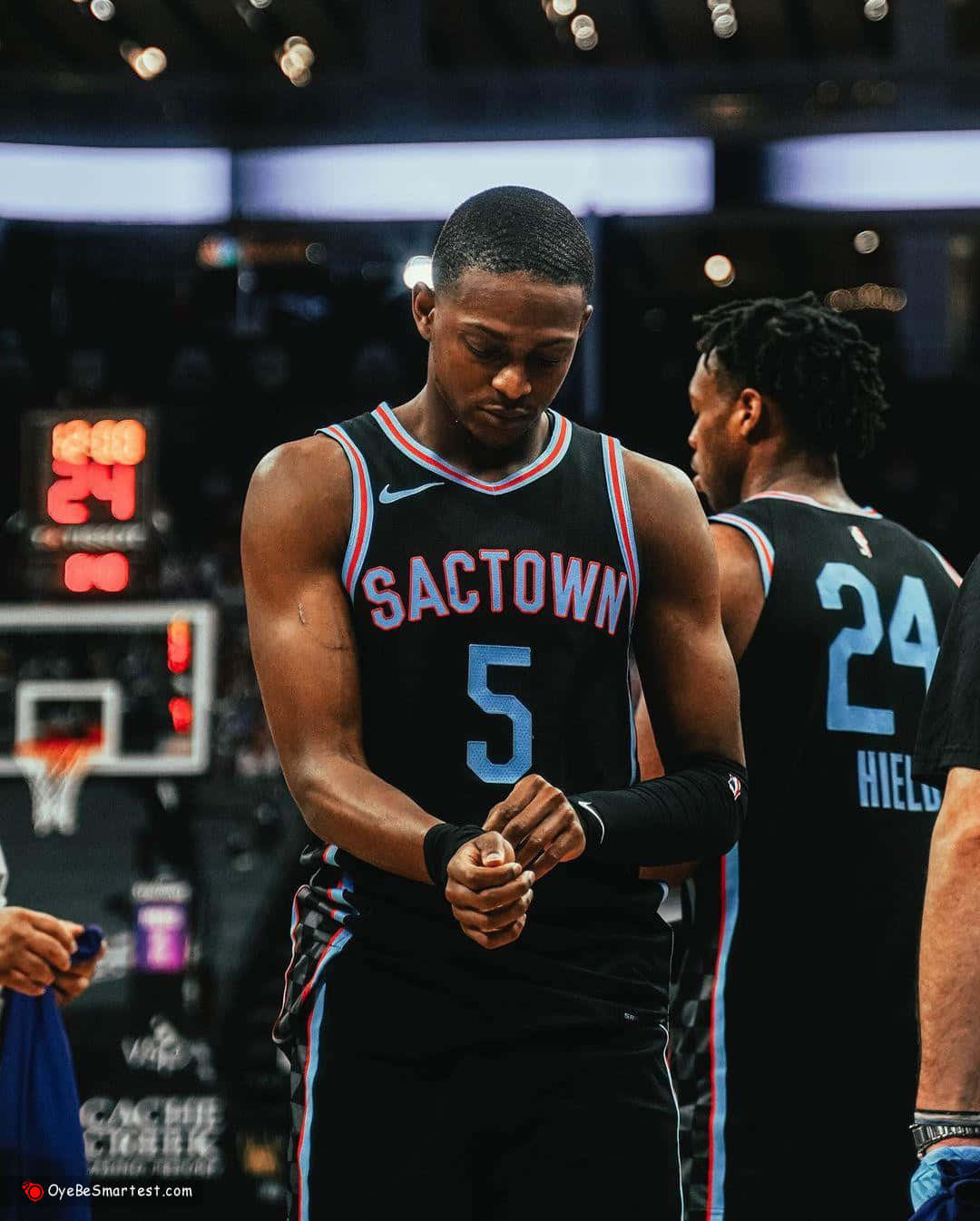 身穿Sactown球衣的籃球運動員在球場上調整護腕。