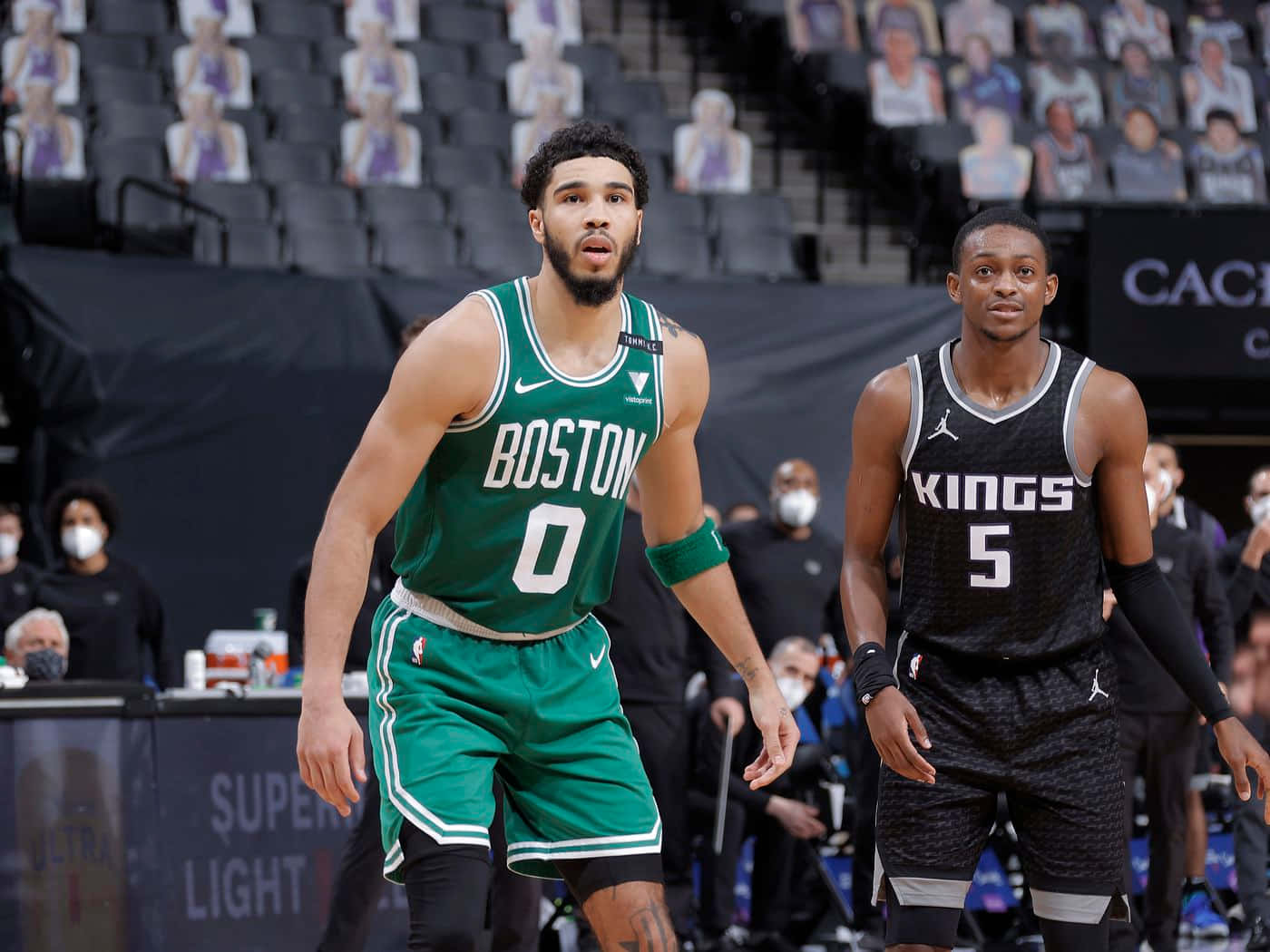 兩名身穿綠色和黑色球衣的NBA籃球運動員在比賽中站在球場上。