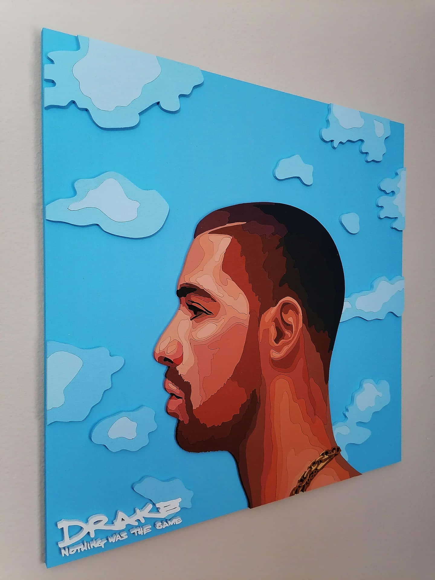 Drake肖像藝術品，帶有藍天白雲，掛在牆上。