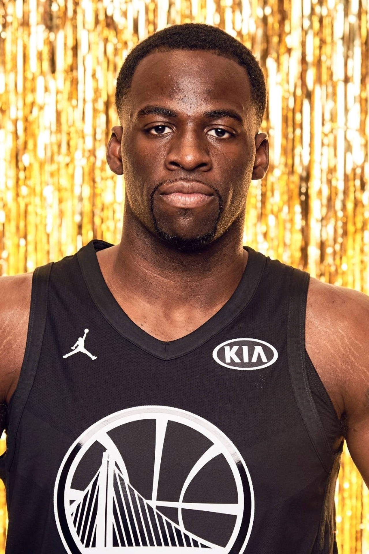 德雷蒙德·格林 2018 NBA全明星賽 壁紙 — 一名身穿黑色球衣的籃球運動員自信地站在閃爍的金色帷幕背景前。