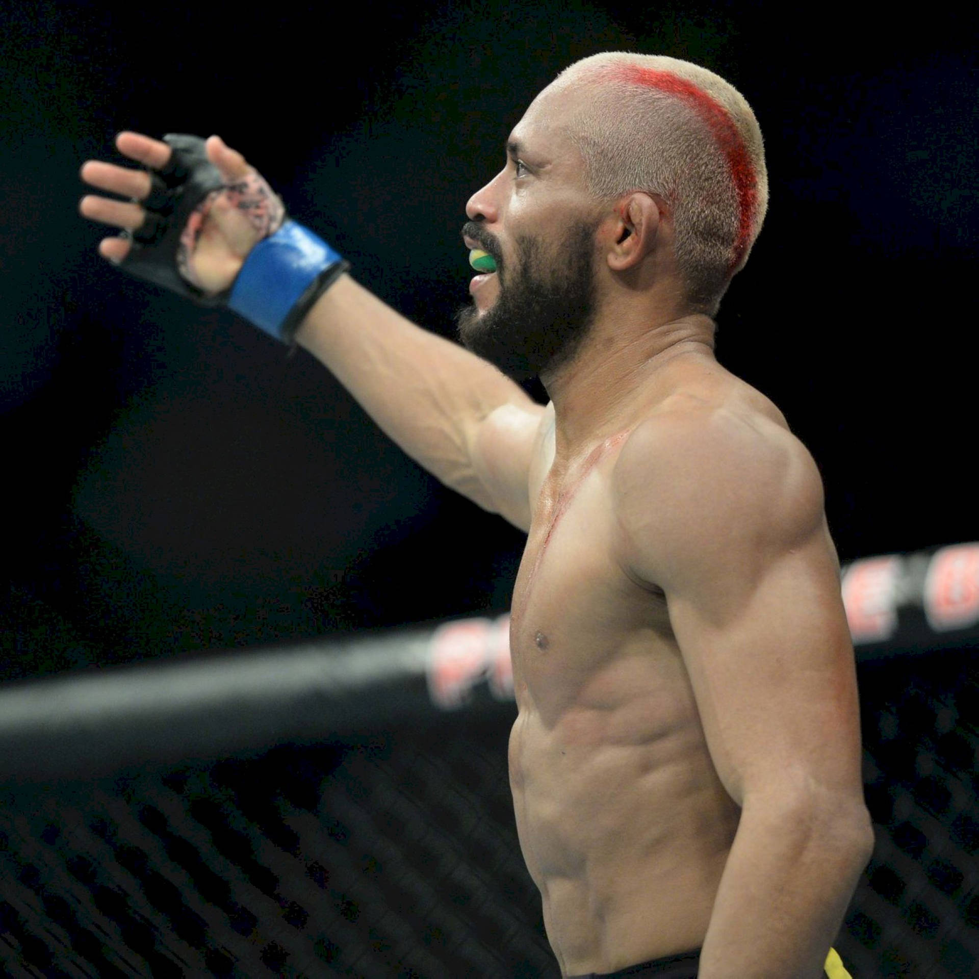 一位勝利的MMA戰士在八角籠內以紅色條紋頭髮慶祝。