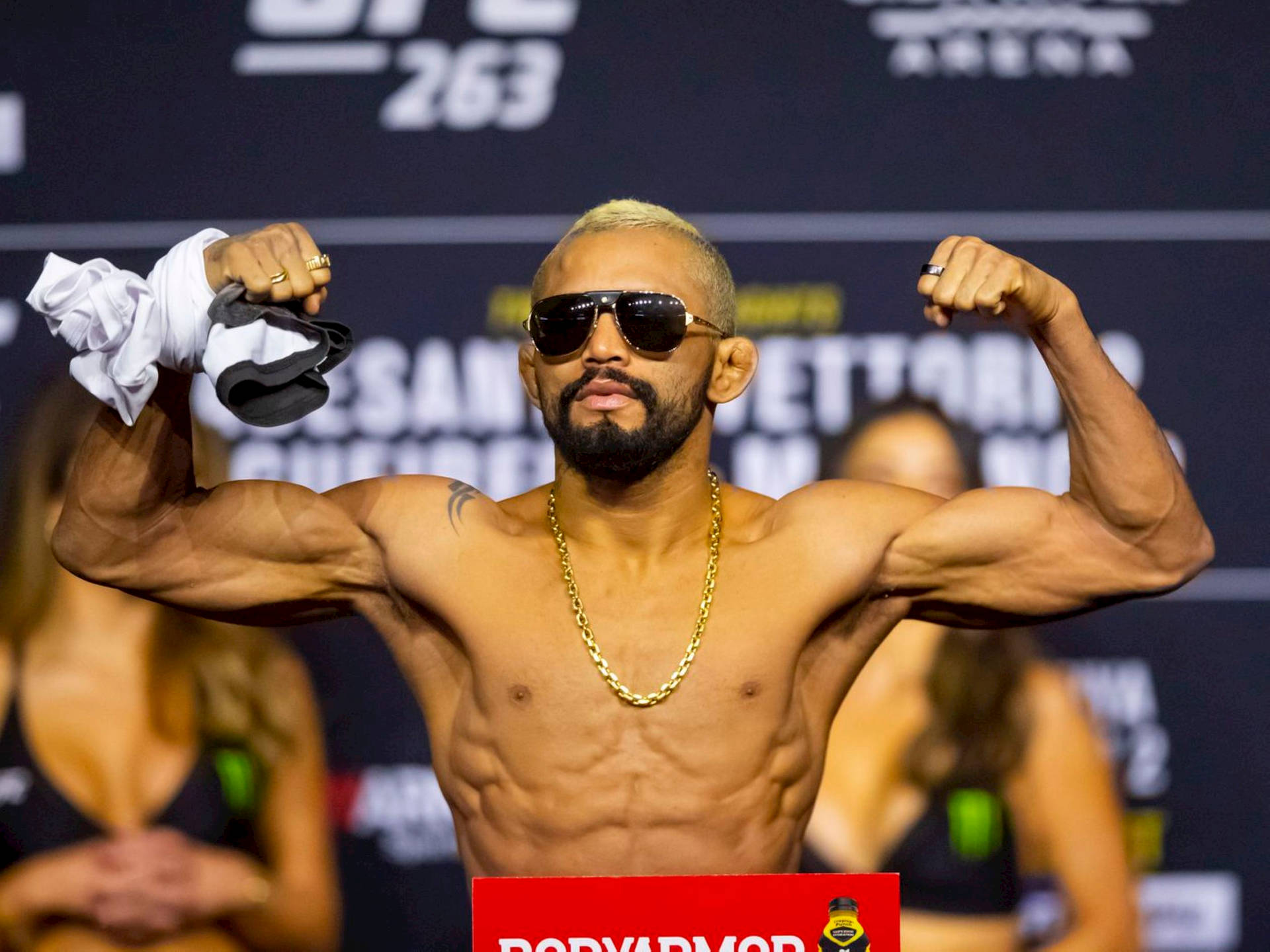 一位赤裸上身的MMA拳手在UFC稱重活動中彎曲手臂展示肌肉。