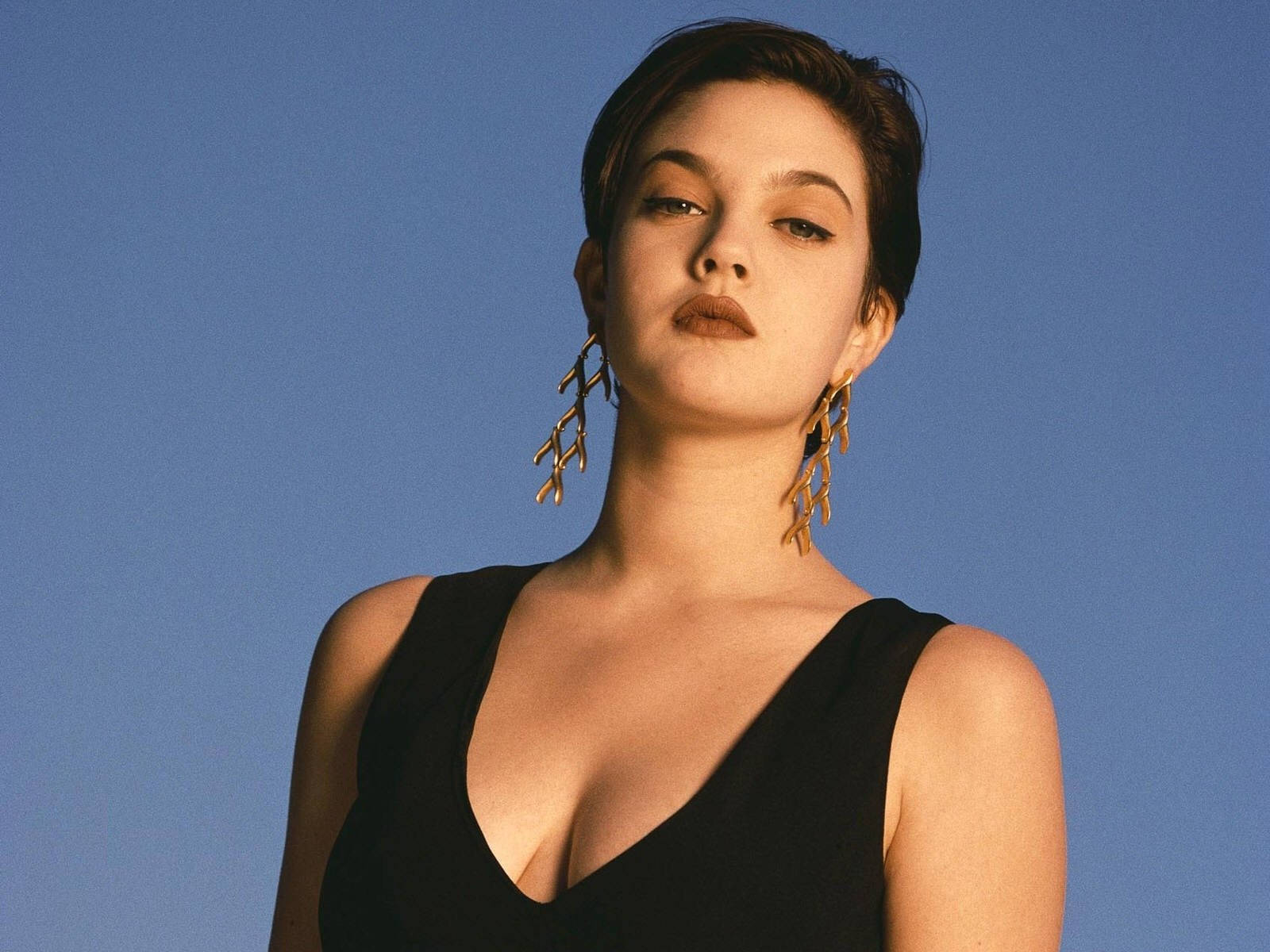 短髮戴金耳環的女性，藍色背景