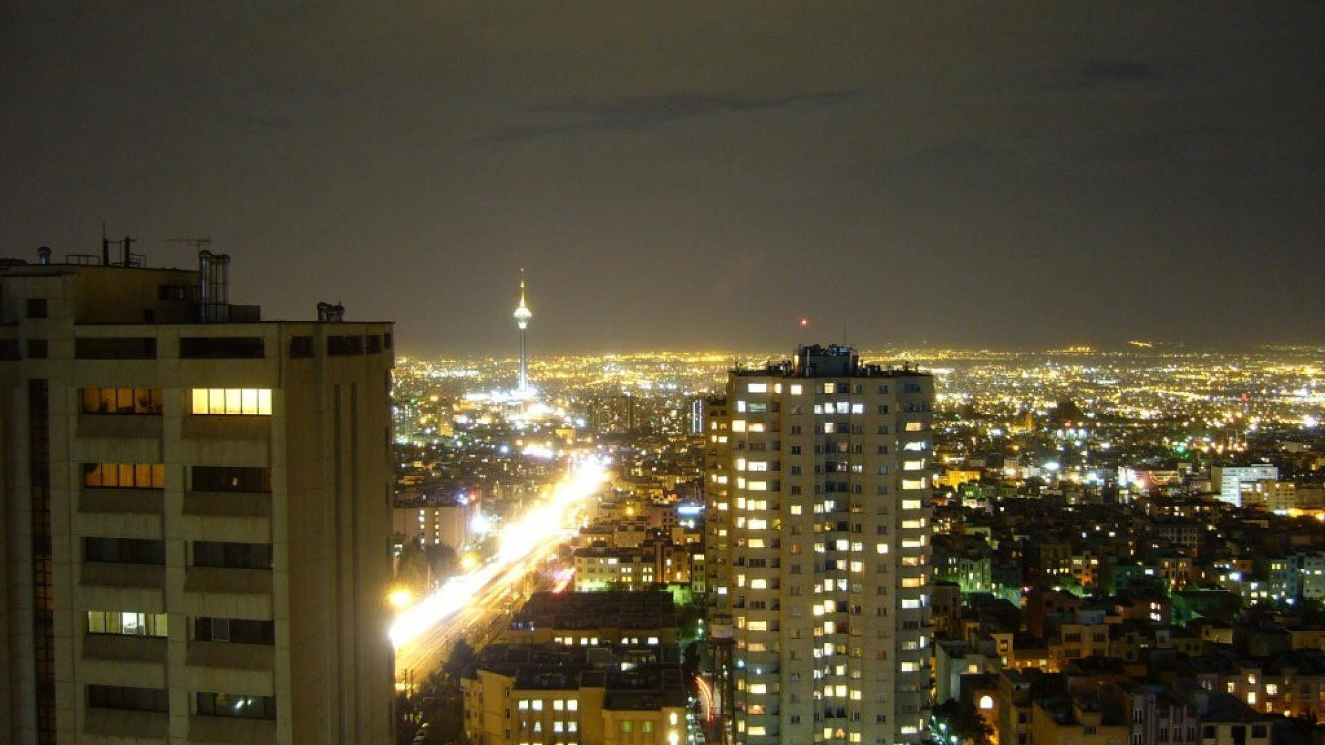 德黑蘭住宅建築 壁紙 — 夜晚廣闊的城市景觀，發光的建築物和一座高聳的地標刺穿黑暗的天空。
