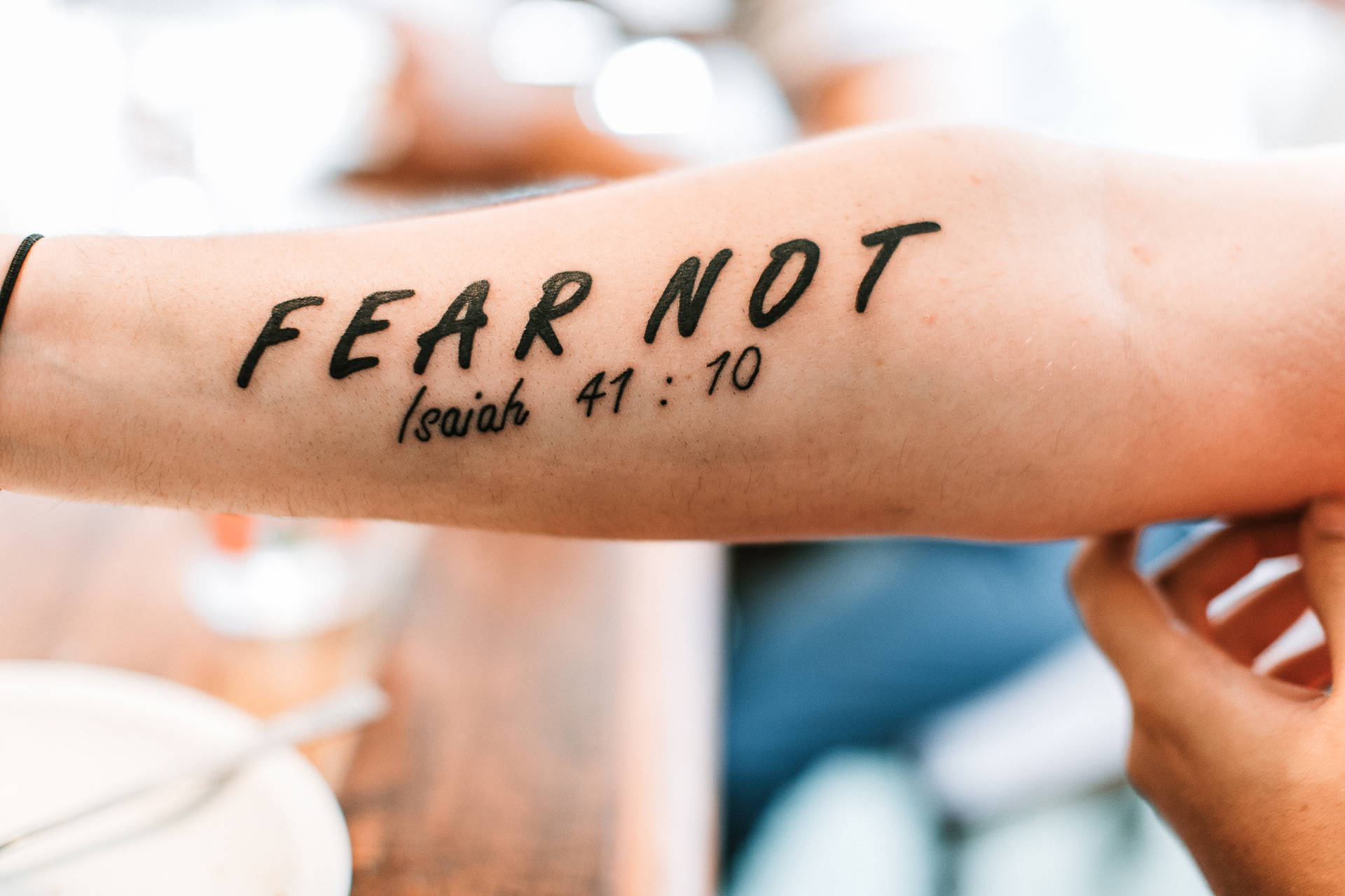 前臂紋身，寫著「FEAR NOT 以賽亞書 41:10」
