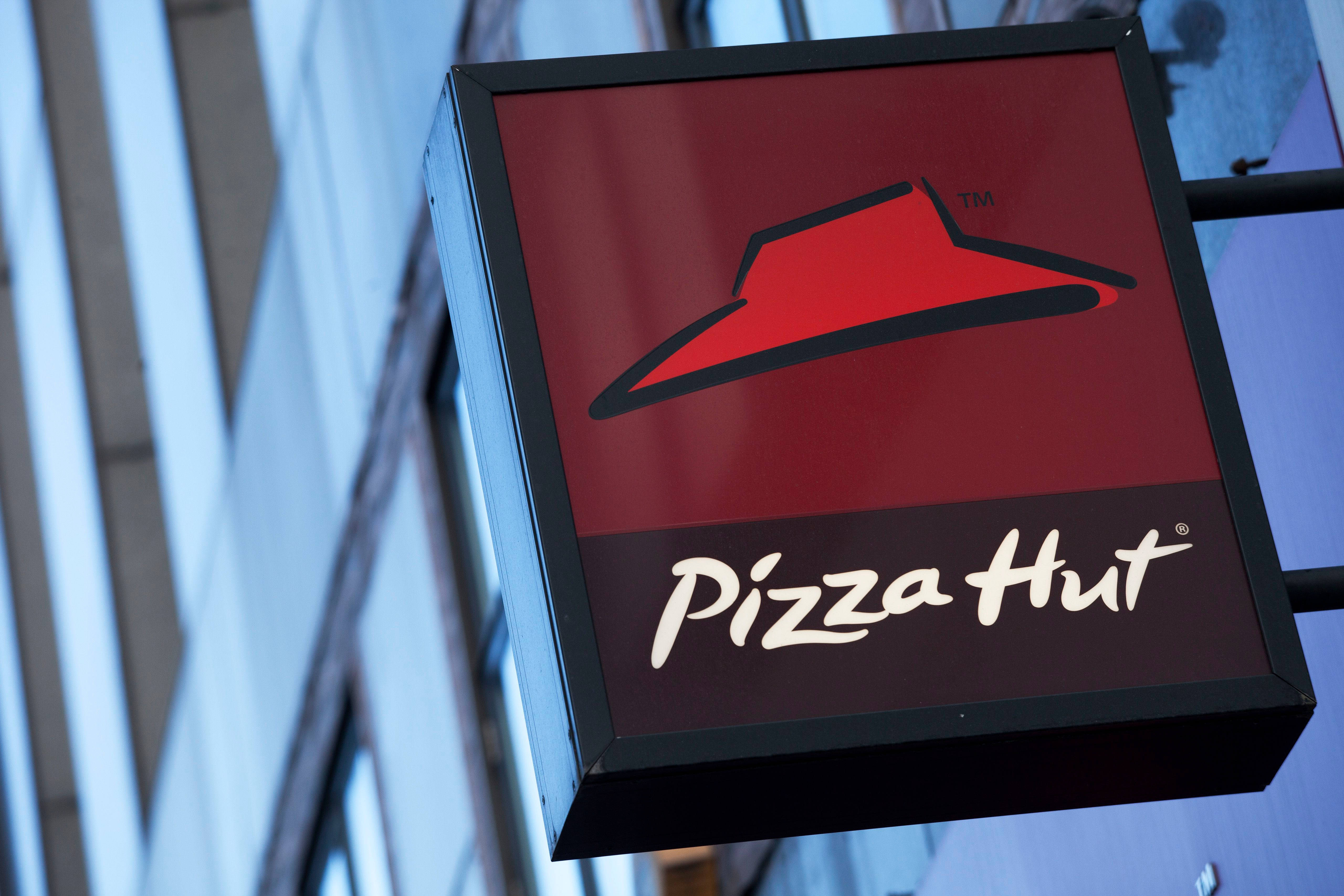 必勝客外掛招牌 壁紙 — 一個紅色Pizza Hut標誌的特寫，帶有黑色邊框，掛在現代玻璃建築外牆上。