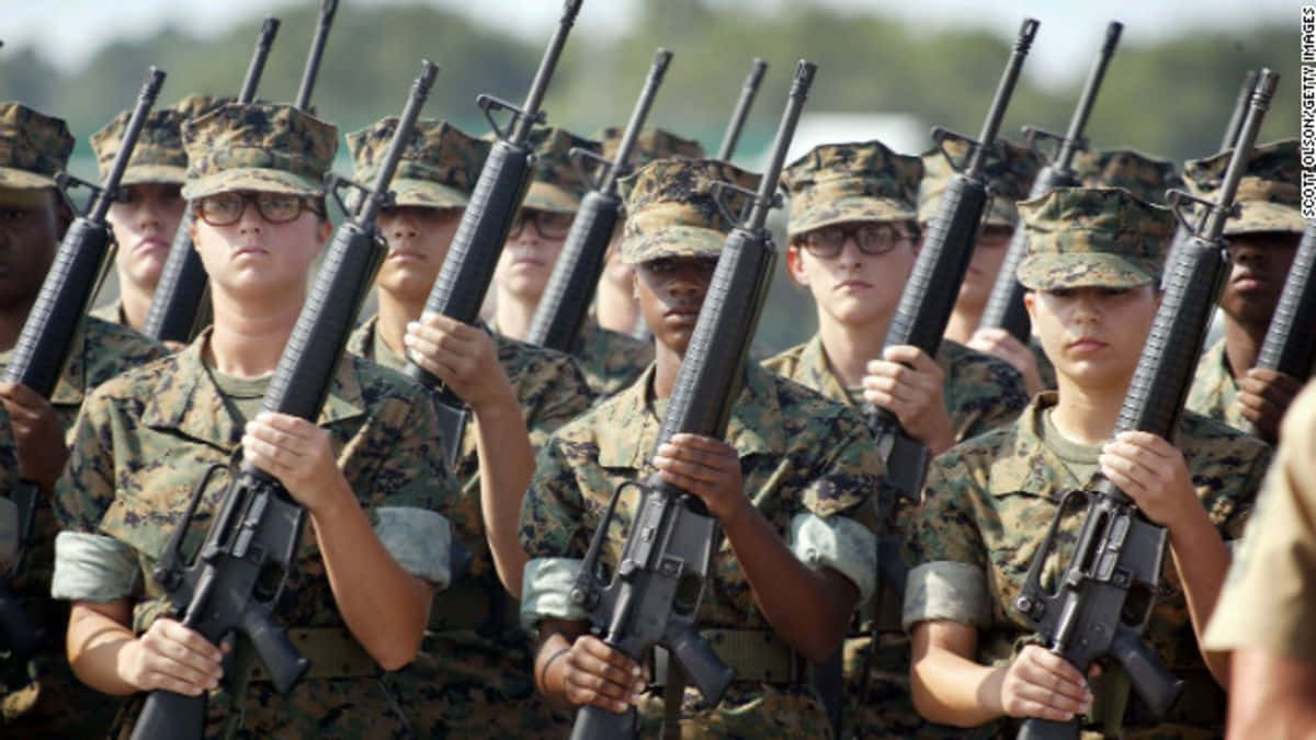 身穿制服的女海軍陸戰隊員在戶外以紀律嚴明的隊形持步槍。