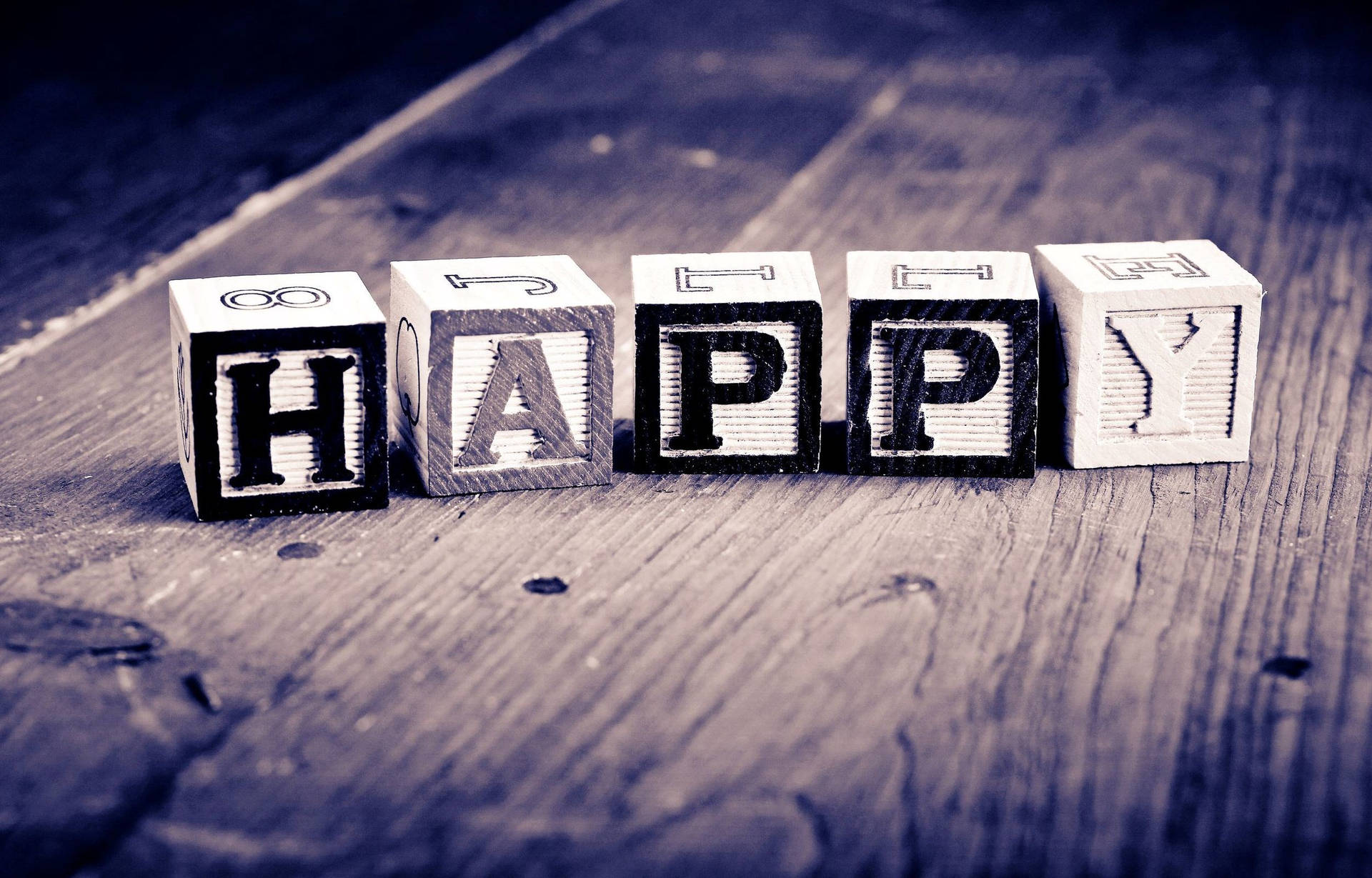 木塊在質樸的木質表面上以藍色調拼出happy。