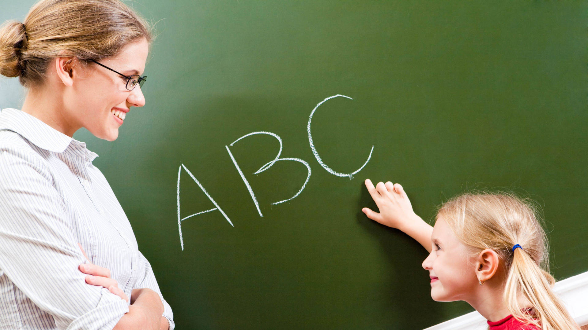 老師和小孩在綠色黑板上學習ABC。