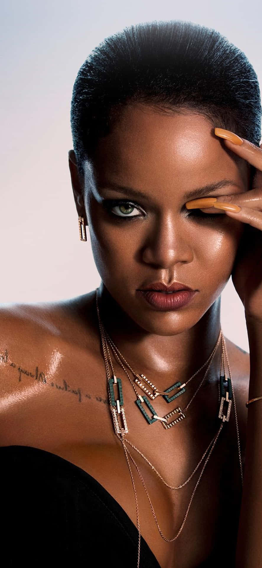 Rihanna 在攝影棚肖像中戴著分層項鍊和金色指甲油。