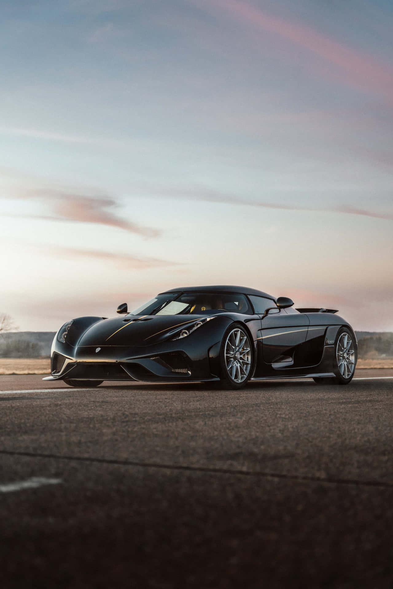 黑色Koenigsegg跑車在瀝青路上，日落時分