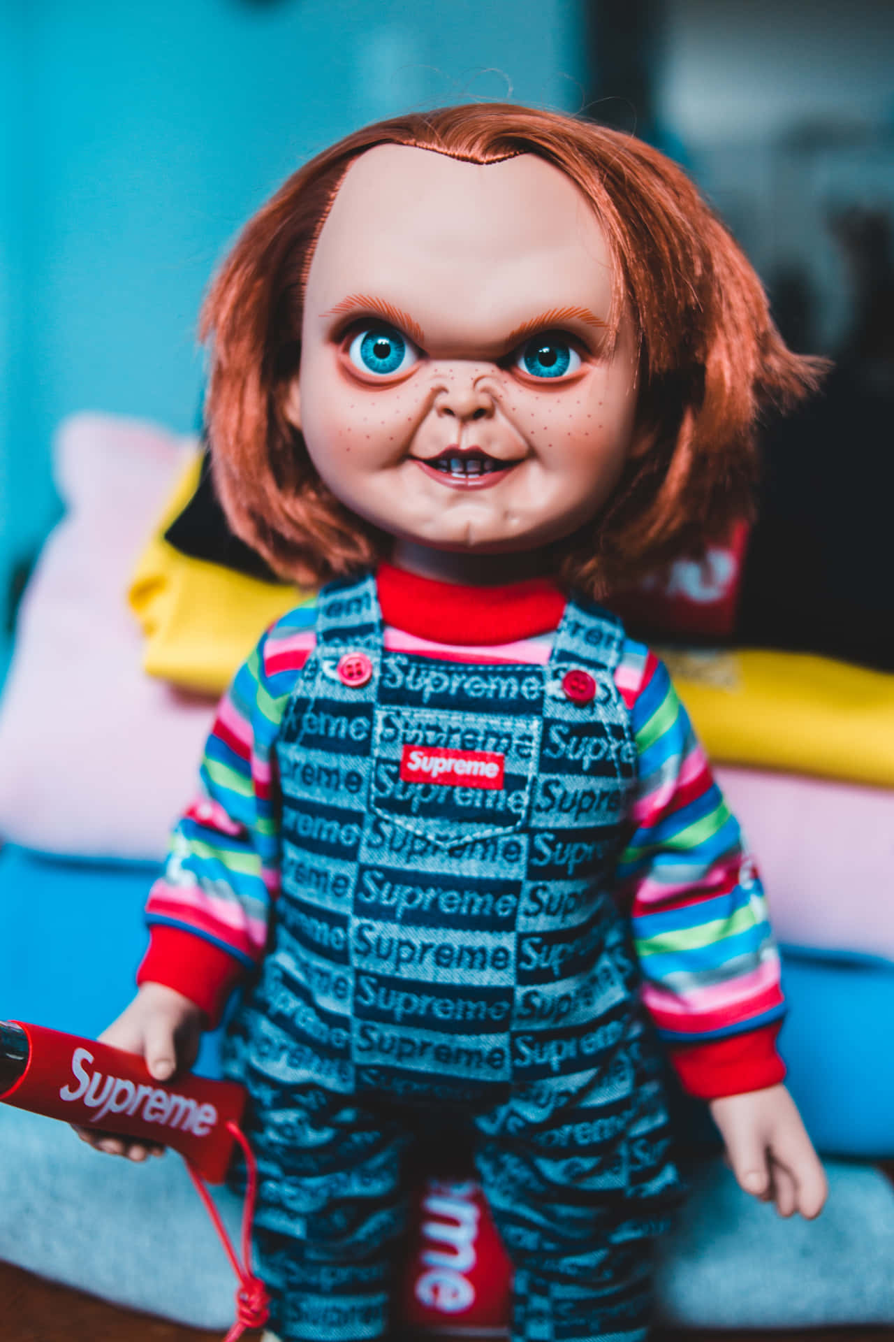 穿著 Supreme 服裝的 Chucky 公仔手持一個紅色 Supreme 盒子。