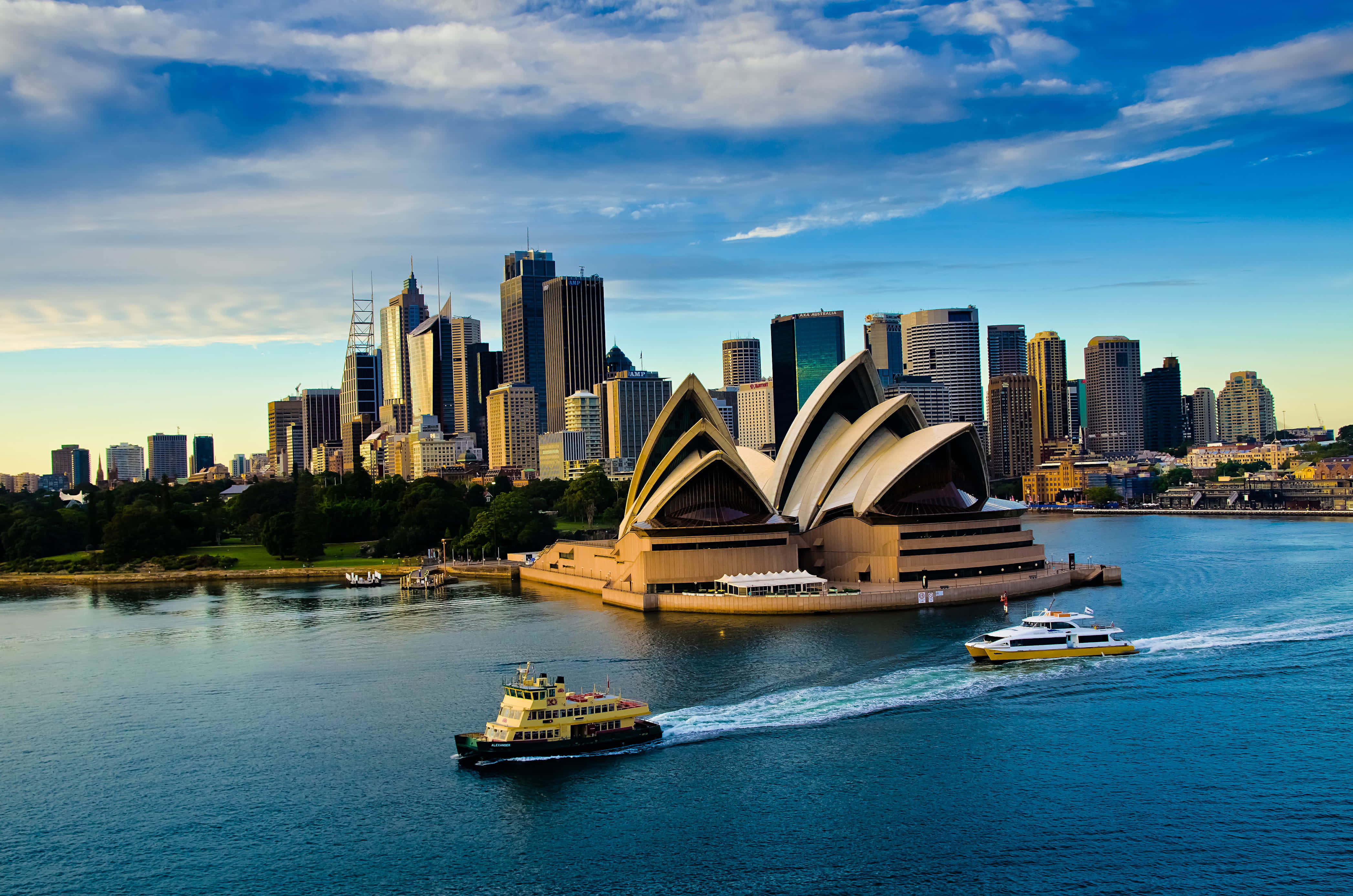 Australia 桌布 壁紙 — 悉尼歌劇院的帆在金色日落、城市天際線和渡輪滑過藍色港灣水面上展現。
