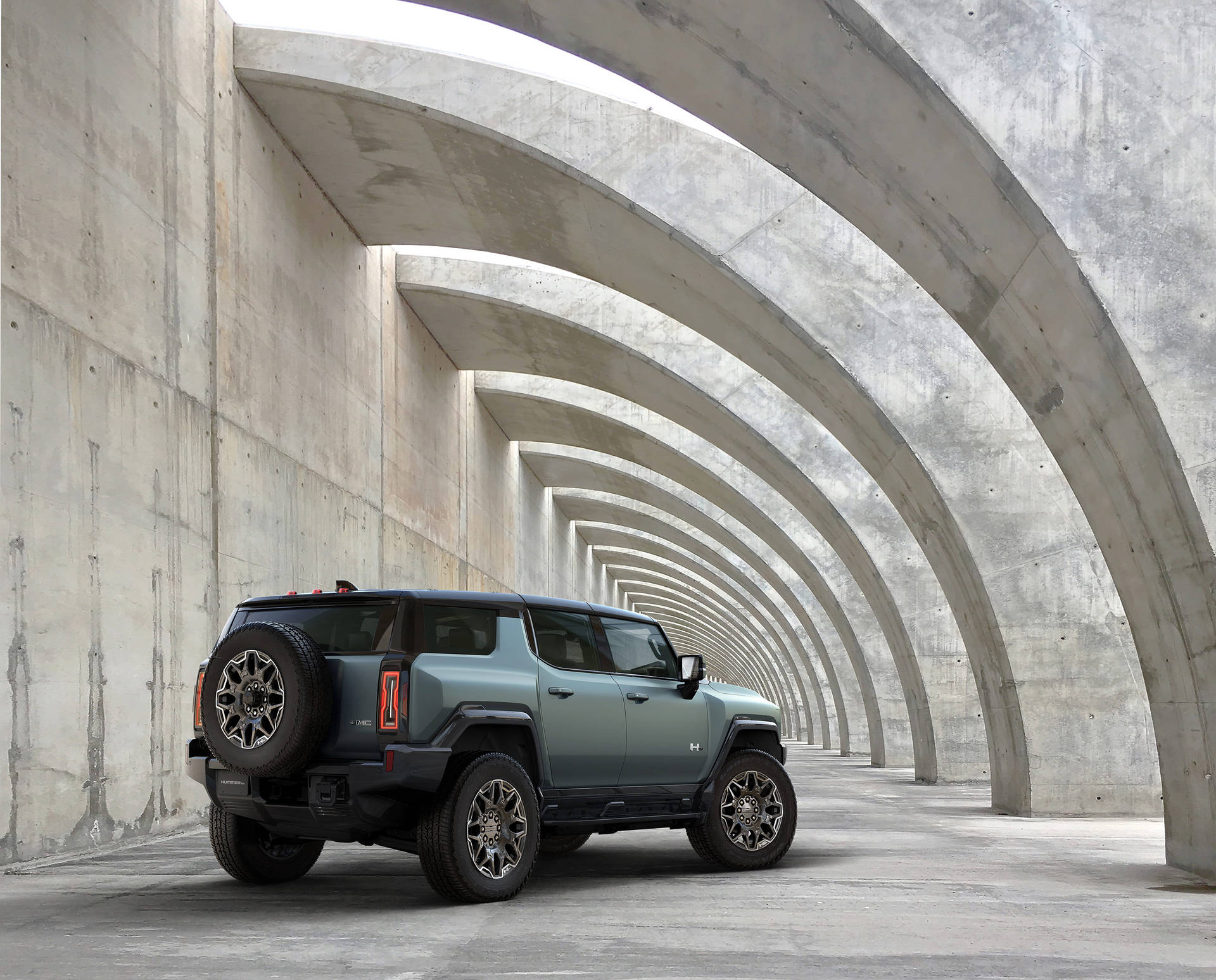 一輛綠色的Hummer EV SUV停放在混凝土拱門隧道下。