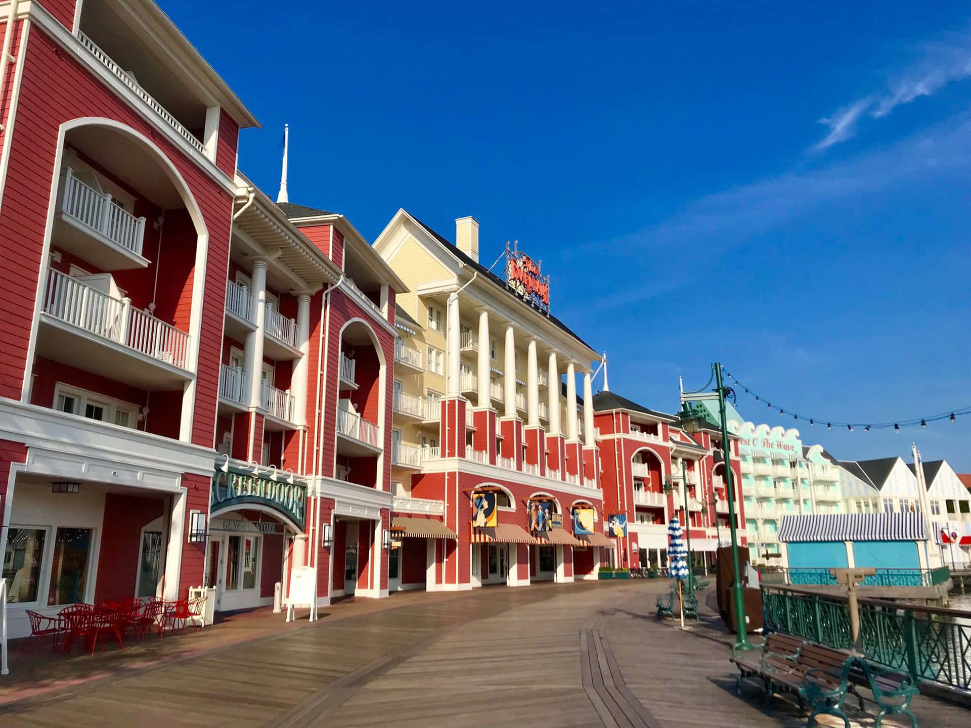 陽光普照的木質木板路旁的紅色和白色度假村建築。