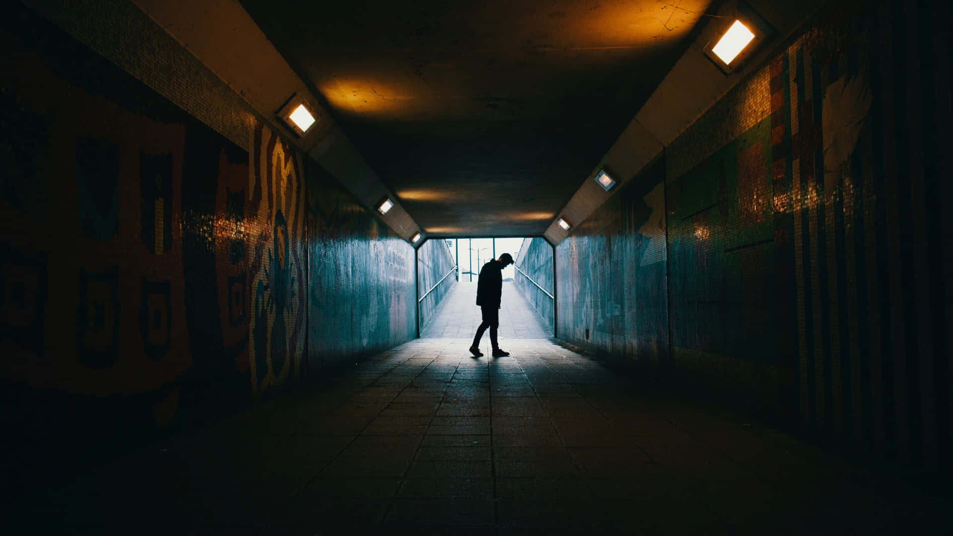 一個人在夜間穿過佈滿塗鴉的城市隧道的剪影。