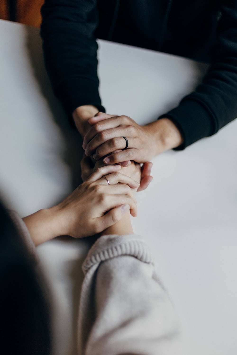 兩個人喺白色枱上拖手，戒指清晰可見