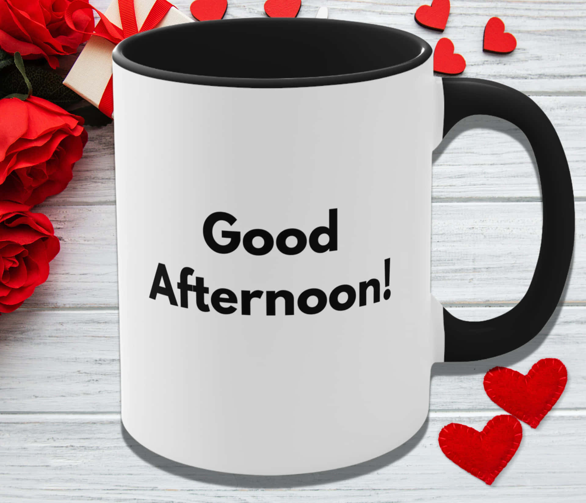 白色馬克杯，黑色手柄，旁邊有紅玫瑰和氈製心形，寫著 'Good Afternoon!'。