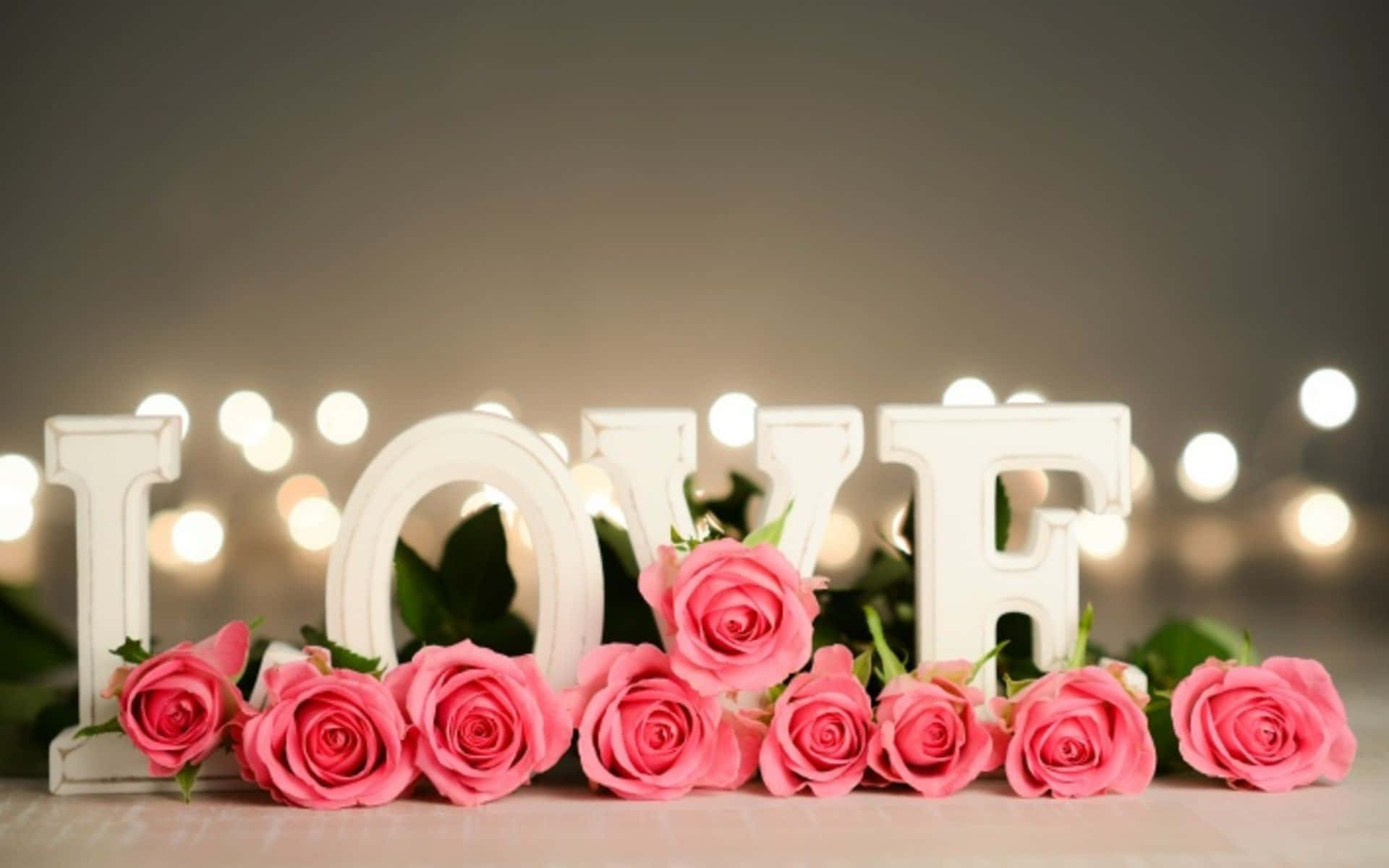 粉紅玫瑰和白色 LOVE 字母，背後有發光的燈光。