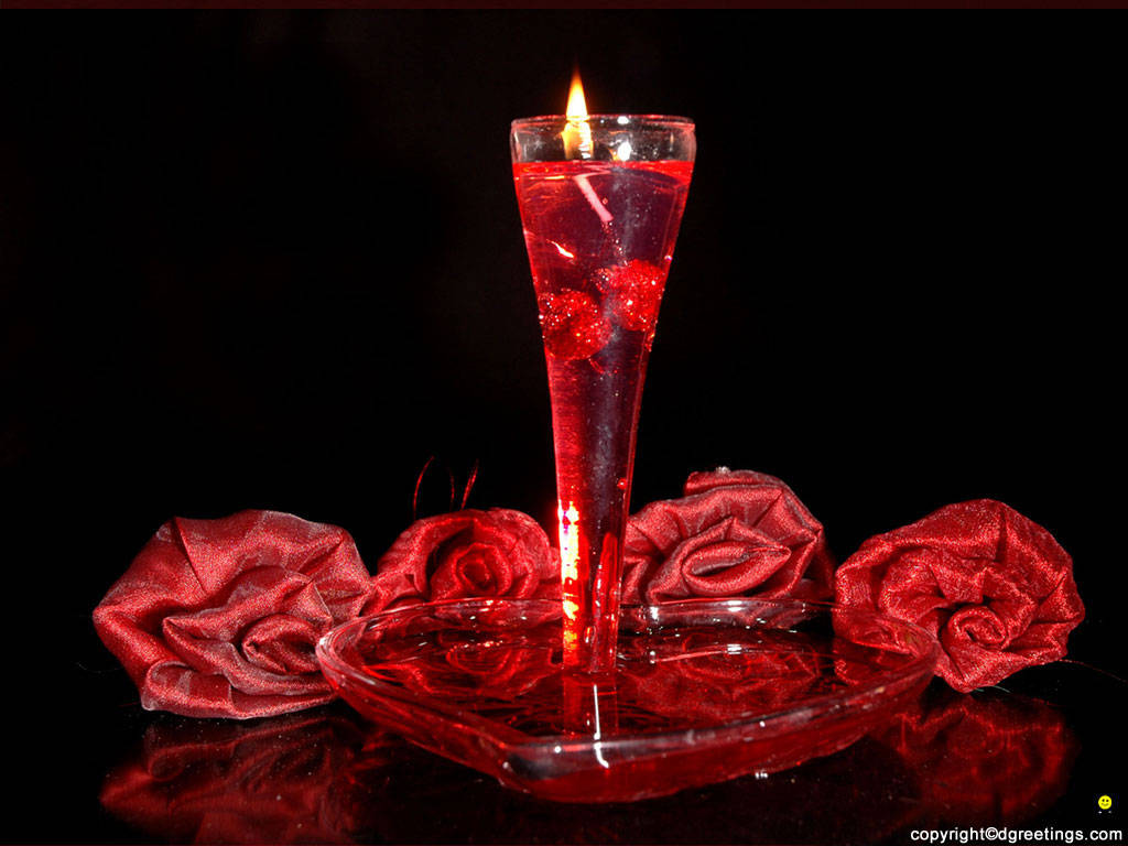 反射表面上的玻璃花瓶中的紅色蠟燭和紅色布料玫瑰。