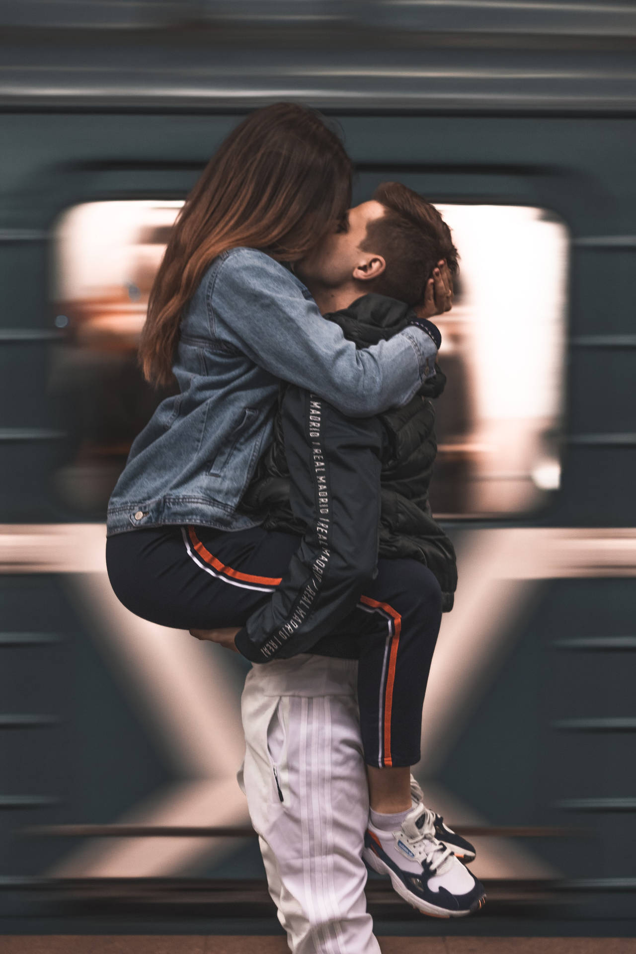 一名男子在行駛中的火車前抱起一名女子並親吻她。