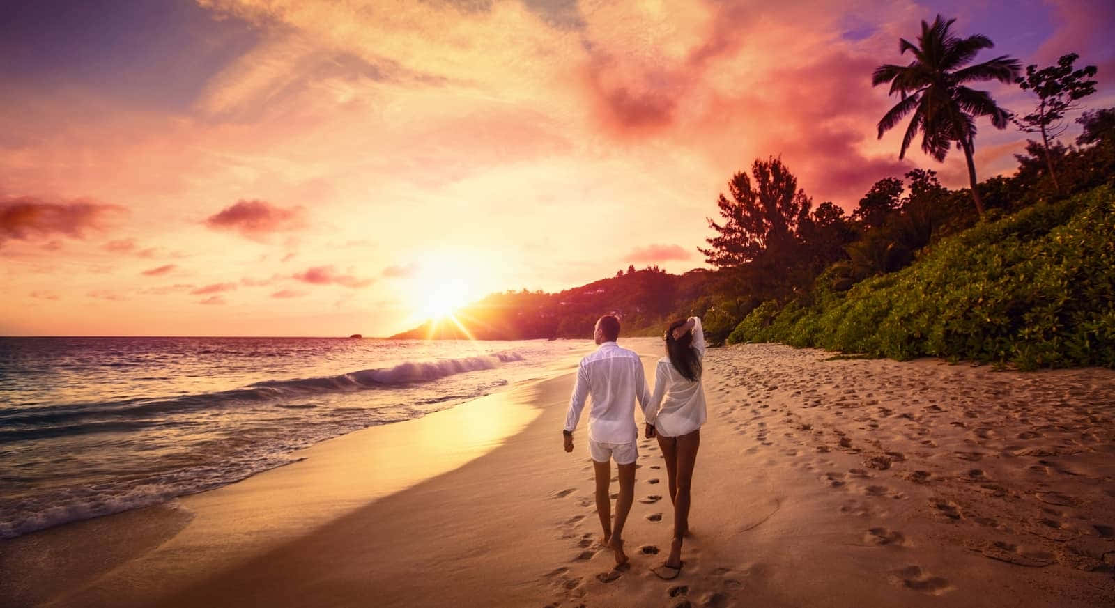 情侶在日落時分於海灘上漫步，伴隨著棕櫚樹和海浪。