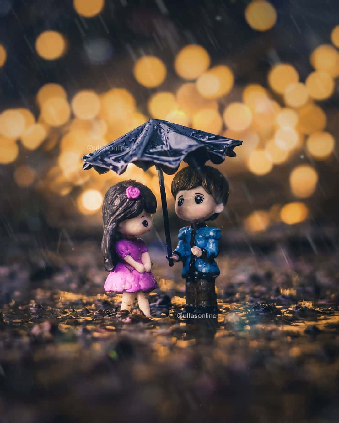 情侶在雨中享受美好時光 壁紙 — 兩個微型人偶在金色散景燈光下共享一把黑色雨傘，雨水落在濕漉漉的地面上。