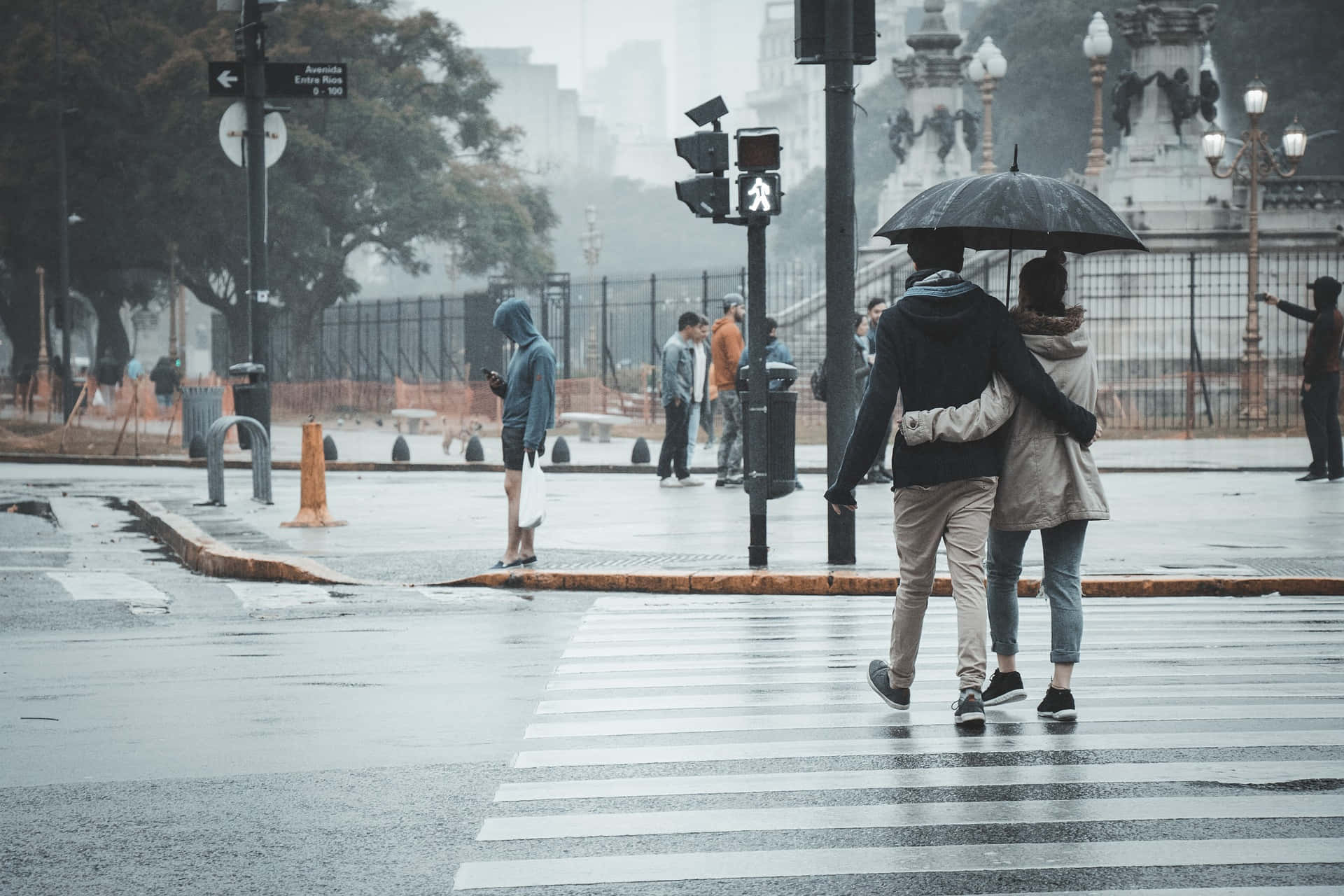 情侶在雨中街道上共用一把傘行走。