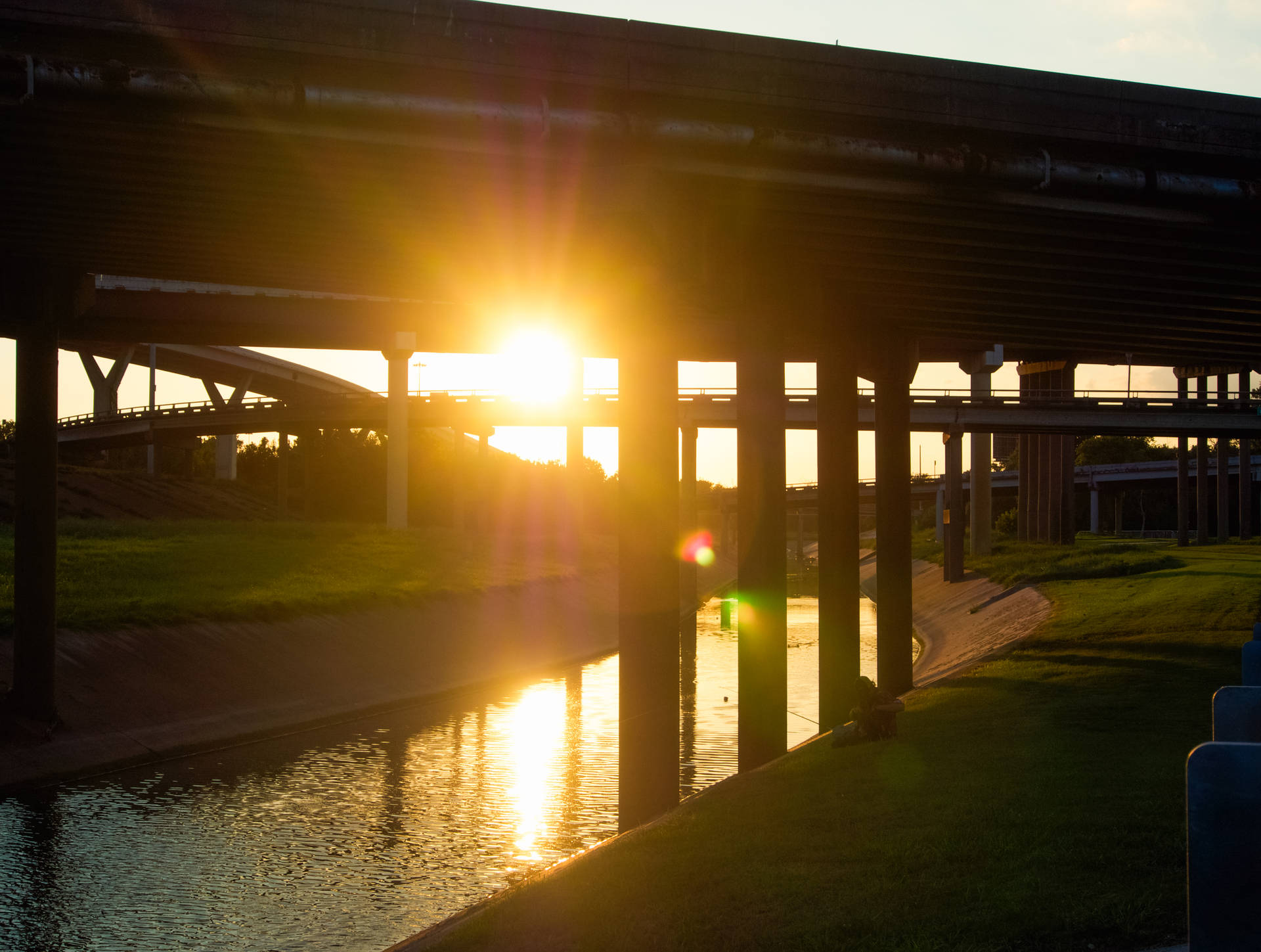 高速公路天橋後的夕陽，河流反射金色光芒