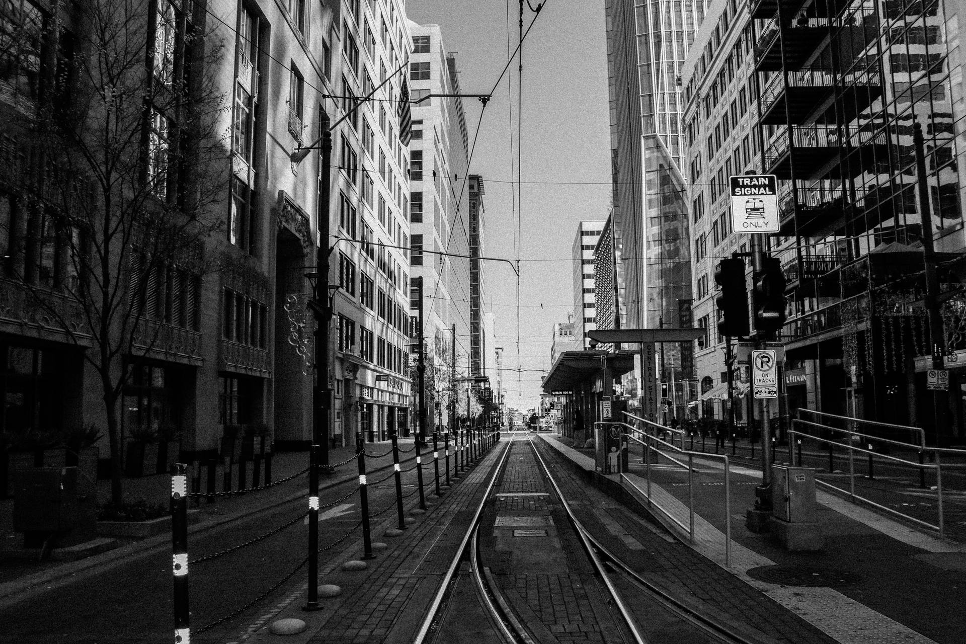 黑白城市街道，有電車軌道和高樓大廈。