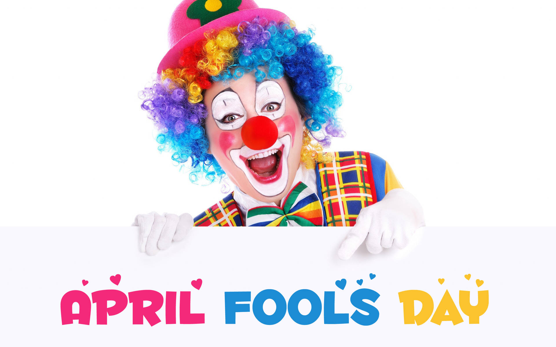 一個微笑的小丑，彩虹頭髮，拿著一個寫著April Fools Day的標牌。