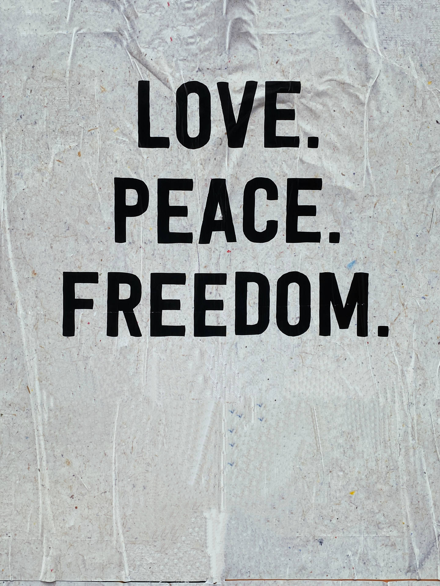 文字壁紙，在皺紋白紙上以粗體黑色字母顯示 love peace freedom。