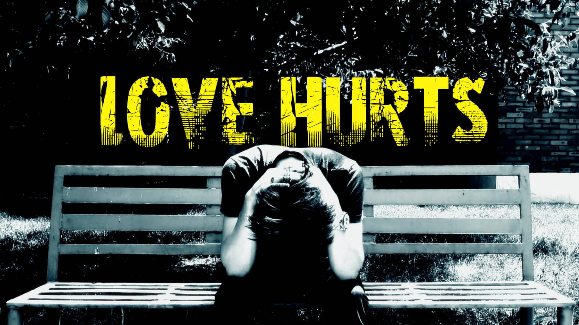 坐在長椅上，在 'LOVE HURTS' 字樣下低着頭的人。