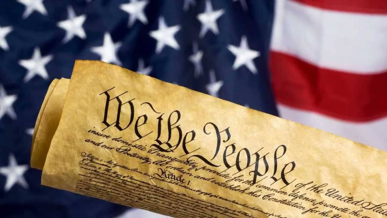 愛國效忠誓詞 壁紙 — 一卷美國憲法羊皮紙，上面有優雅字體的「We the People」，背景是模糊的美國國旗。