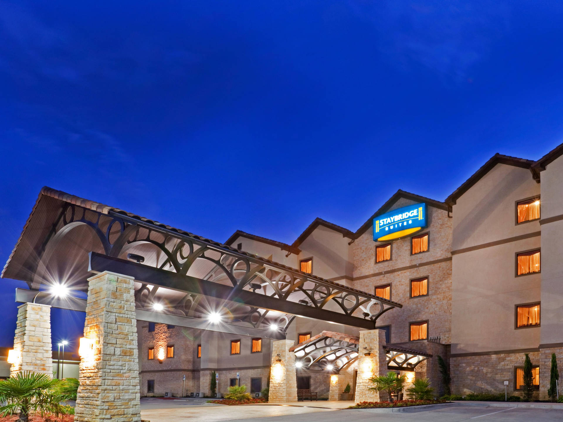 暮色中的 Staybridge Suites 酒店，窗戶明亮，石拱門。