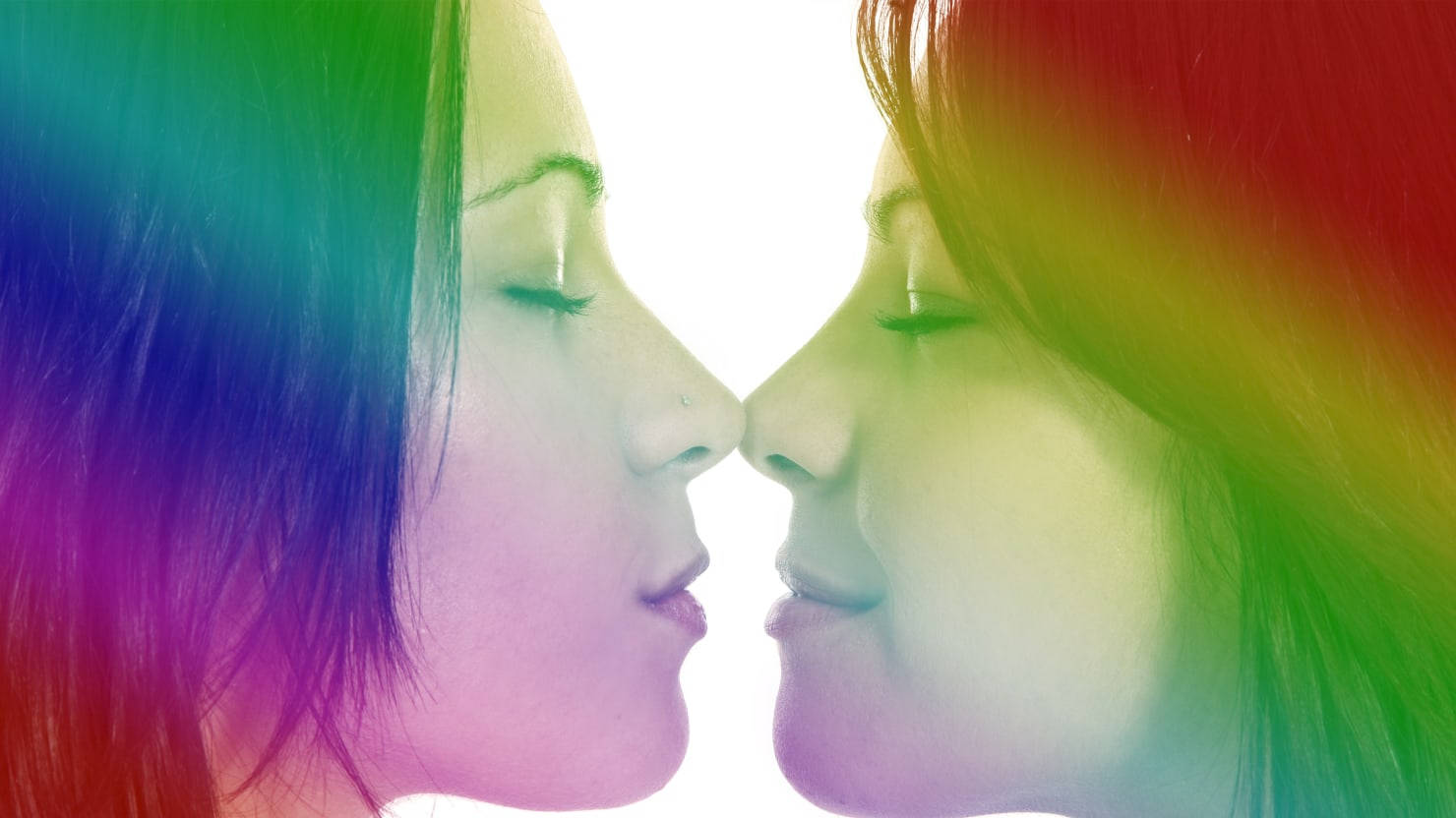 愛是愛 LGBTQ情侶 壁紙 — 兩位擁有彩虹色頭髮的女性在明亮的白色背景前溫柔地觸碰鼻子，展現溫馨時刻。