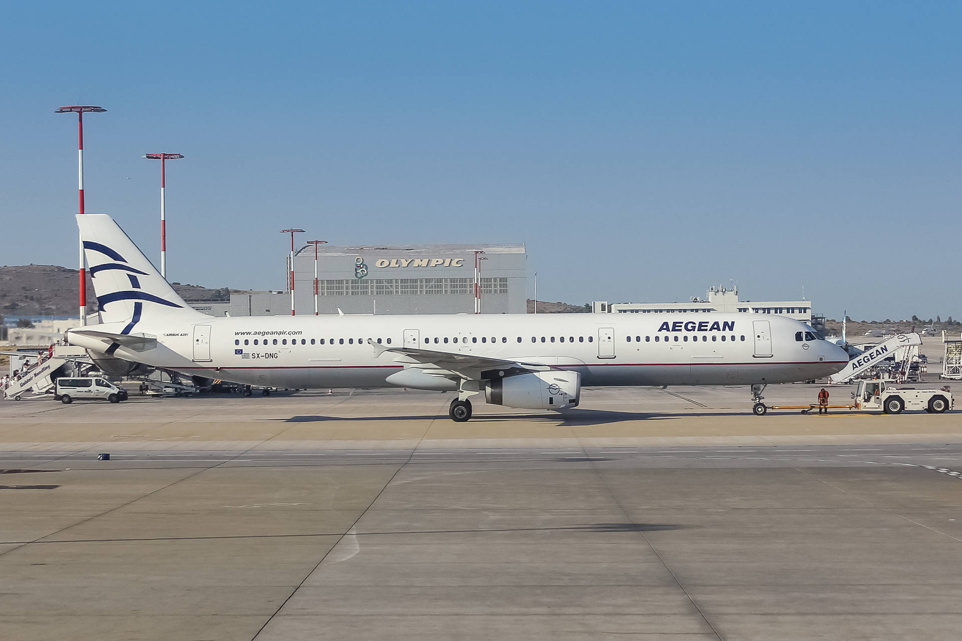 愛琴海航空飛機停在機場閘口，背景有奧林匹克建築。