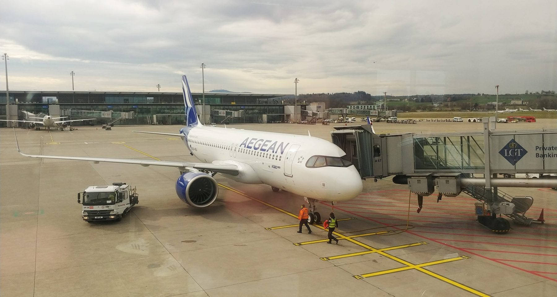 愛琴海航空飛機在機場閘口，有地勤人員和登機橋。