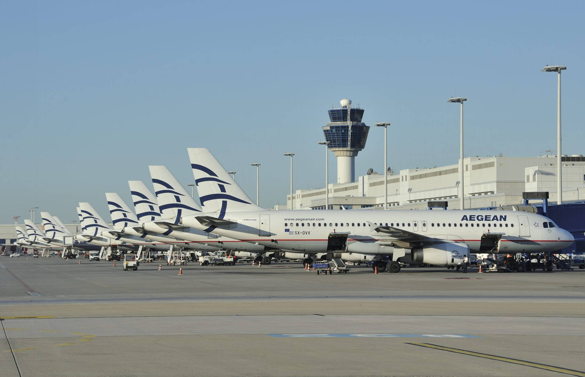 一排愛琴海航空的飛機在白天停在機場航站樓。