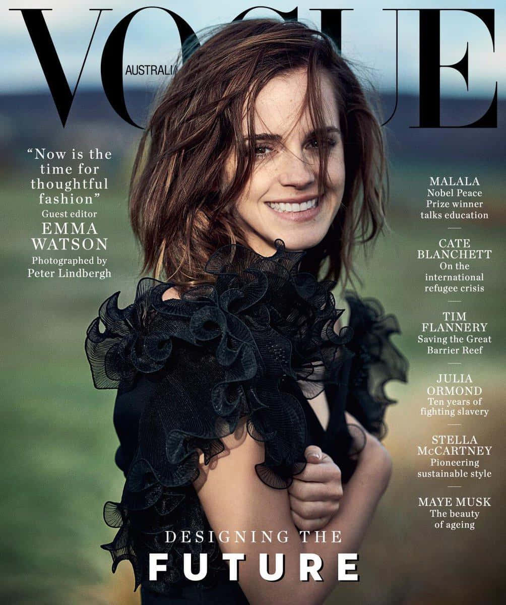 愛瑪·屈臣 桌布 壁紙 — 愛瑪屈臣在Vogue Australia封面上，穿著黑色荷葉邊連衣裙，在模糊的綠色田野背景下燦爛微笑。