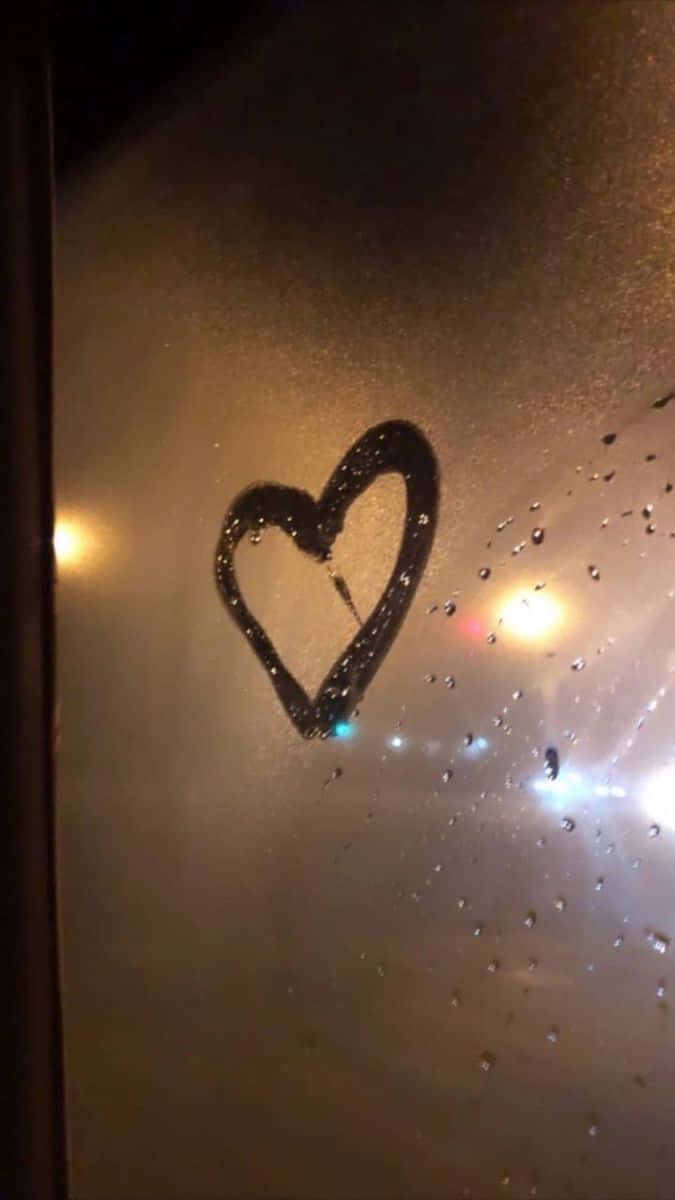 愛自己！ 壁紙 — 在雨中窗上畫的心形，溫暖發光的燈光透過濕玻璃反射。