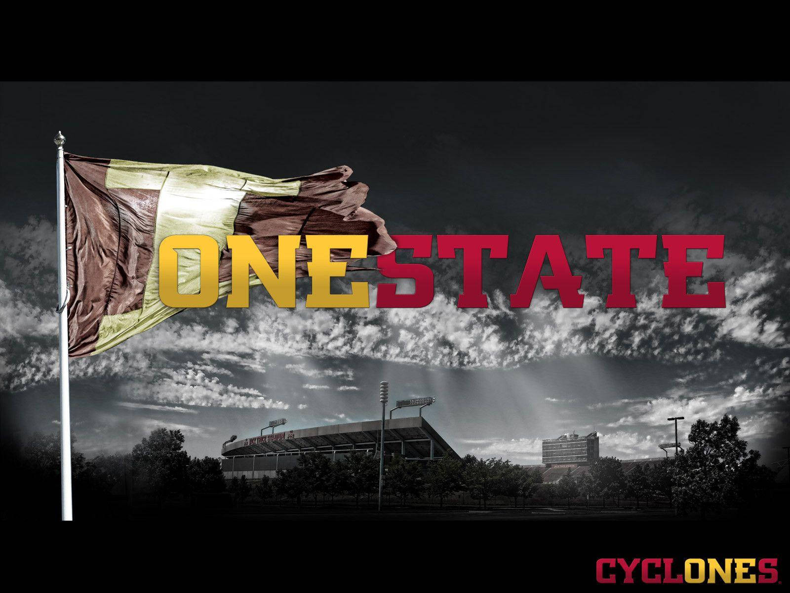 旗幟在體育場上空飄揚，以多雲天空為背景，帶有「ONE STATE」文字。